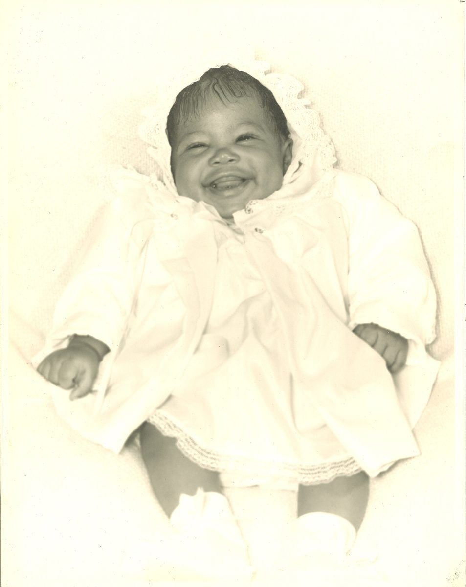 A laughing baby in a white christening gown