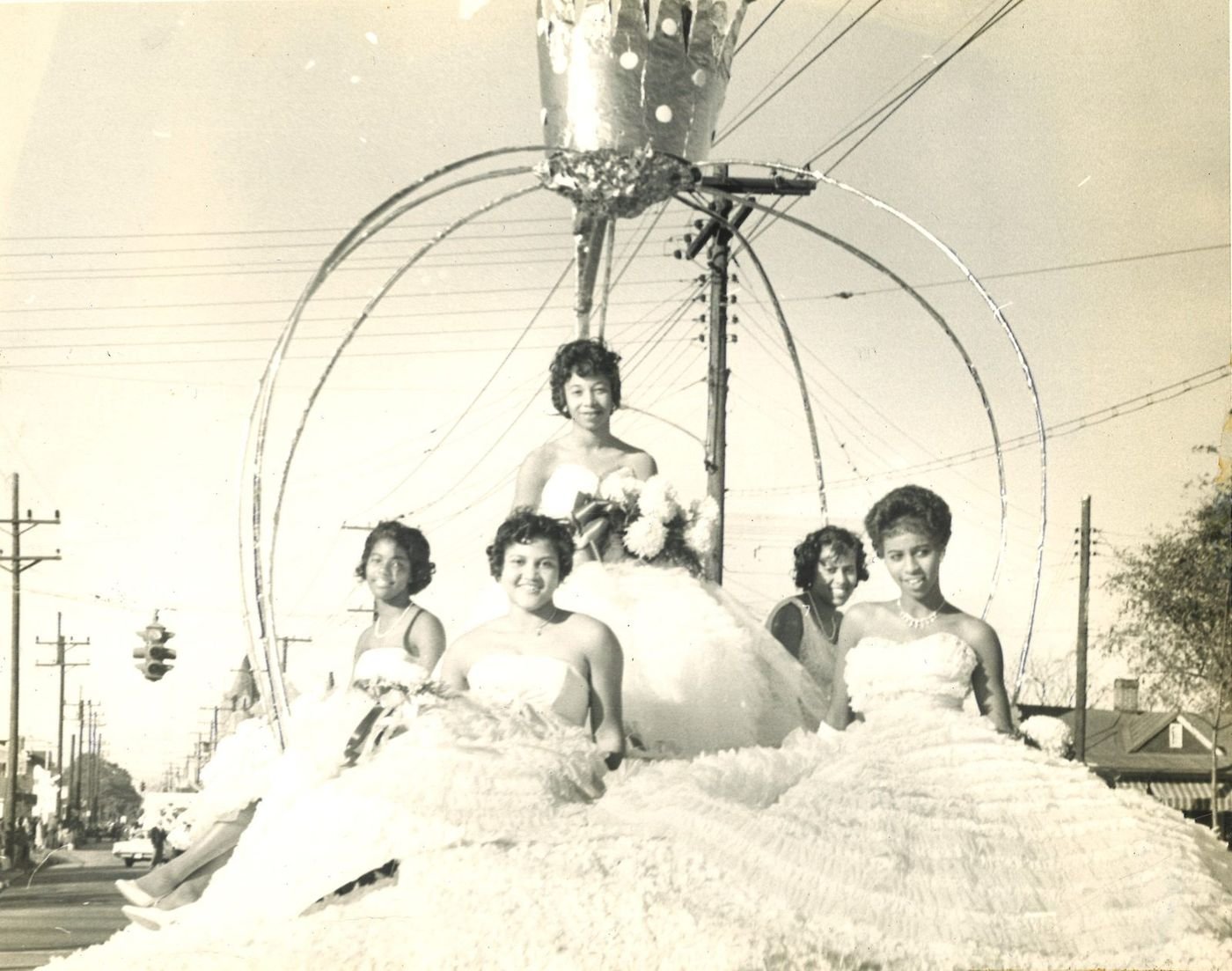 Carolyn on a parade float in a white gown under an arched crown, with four other young women