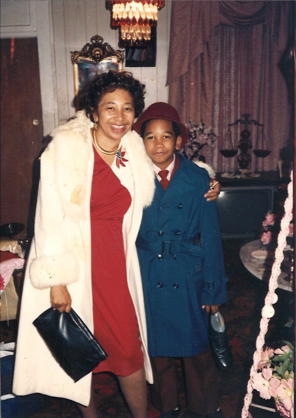 Carolyn in a red dress and white fur coat with young Marcus in a blue coat and red hat