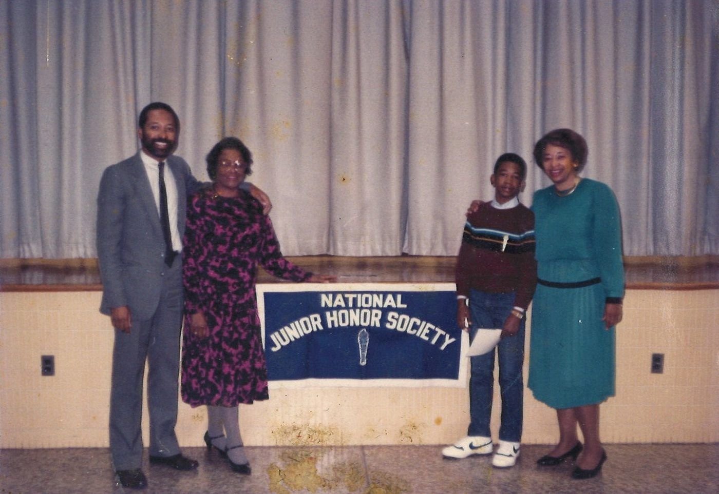 Carolyn with young Marcus beside a National Junior Honor Society banner, with another couple