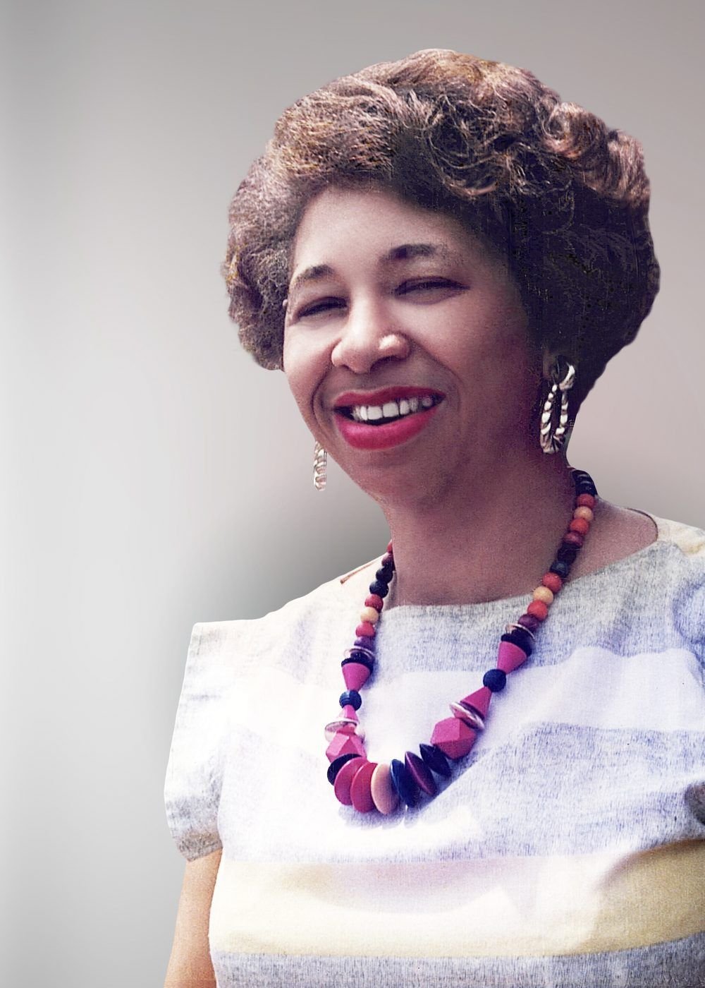 Carolyn Williams Bell smiling broadly, wearing a beaded necklace