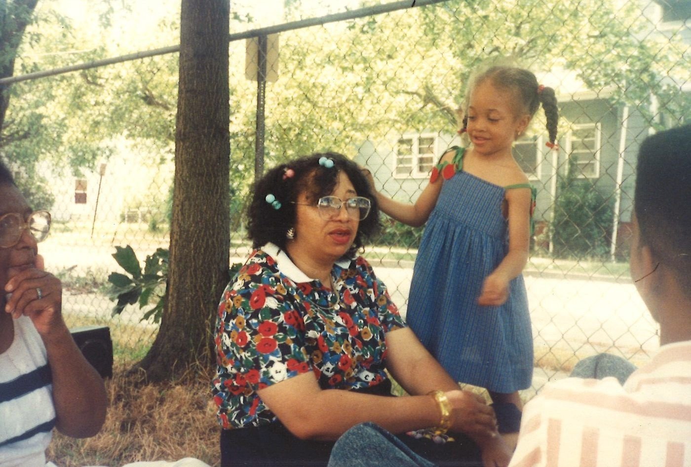 Carolyn in a floral dress outdoors with a small girl in a blue dress standing beside her